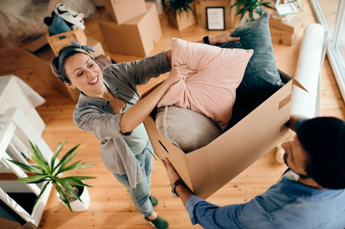 Professional mover in uniform carrying moving boxes