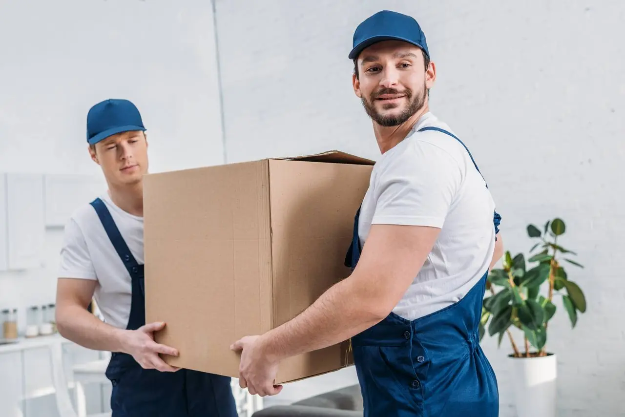 Moving team carrying large box to new home in Frisco, TX